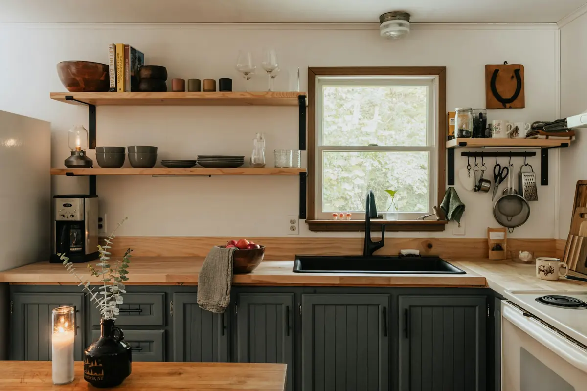 Cocina luminosa con estantes abiertos de madera, velas y una ventana